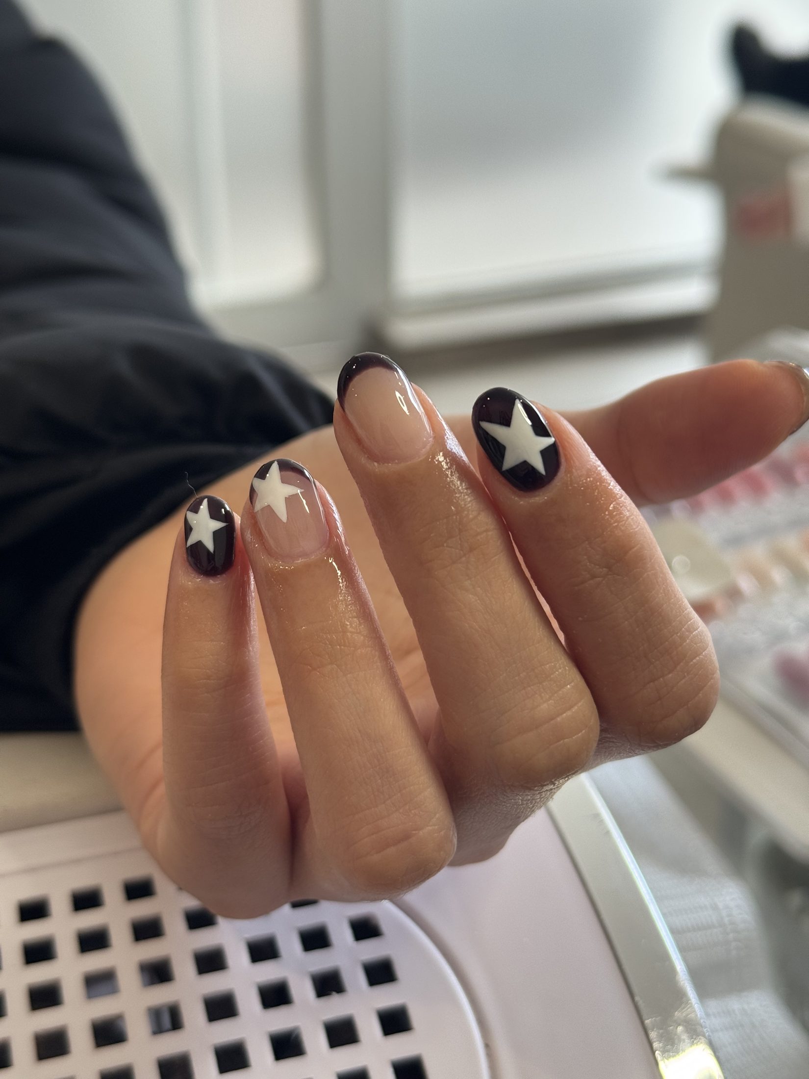 Diseño de uñas nude y oscuro con detalles de estrellas